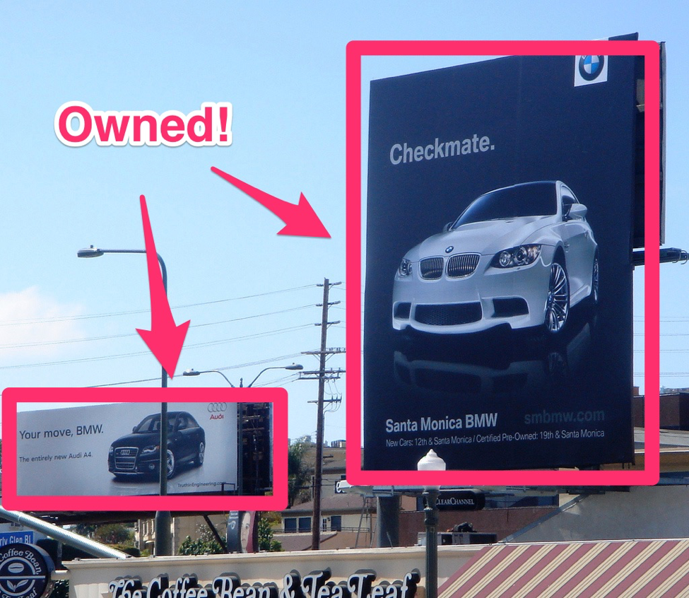 An image of 2 billboards next to each other, one for Audi and one for BMW.