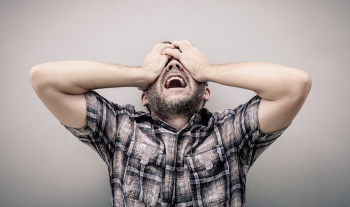 portrait one sad man standing near a wall and covers his face