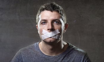 attractive young man with mouth sealed on duct tape to prevent him from speaking