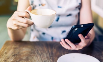 close up hand woman using smartphone in coffee shop with depth of field