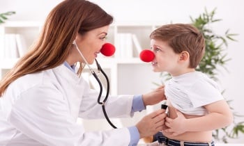 Smiling adorable female doctor clown listen patient heart