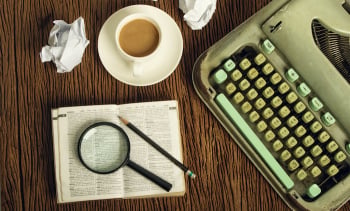 The dictionary consider under a magnifier on writer’s desk with crumpled sheets around