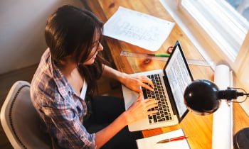 Young female blogger working at home.She sitting in her working room and typing something on laptop.