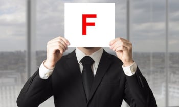 businessman in suit holding up sign with letter f