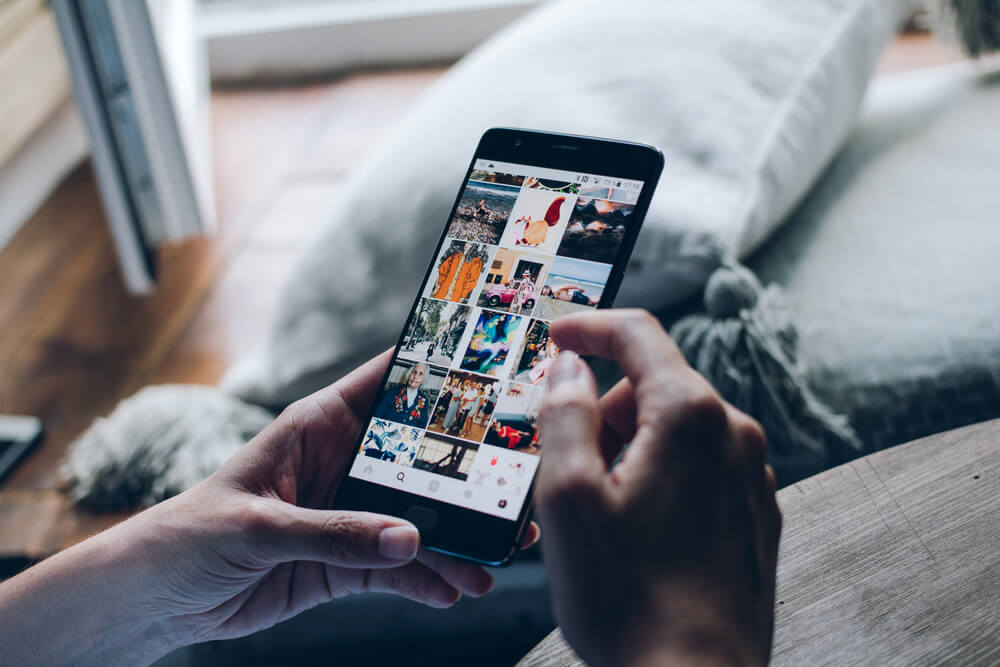 homem segurando smartphone com feed do aplicativo instagram en tela