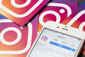 como anunciar no instagram: smartphone com perfil no aplicativo instagram em tela com icones do aplicativo ao fundo