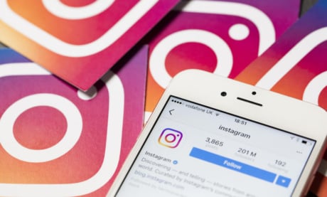como anunciar no instagram: smartphone com perfil no aplicativo instagram em tela com icones do aplicativo ao fundo