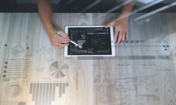 top view of Designer hand working with digital tablet computer with design diagram layer effect on wooden desk as responsive web design concept