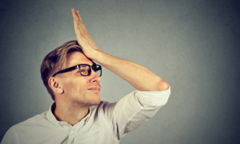 Silly man slapping hand on head having duh moment