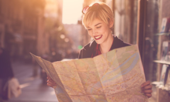 Young beautiful female traveler standing on the street and looking at the map
