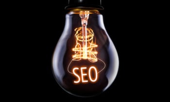 Hanging lightbulb with glowing SEO concept.