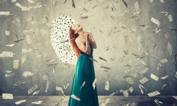 Happy woman with umbrella under a money rain