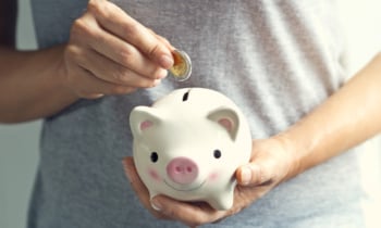 Woman hand putting coin into piggy bank