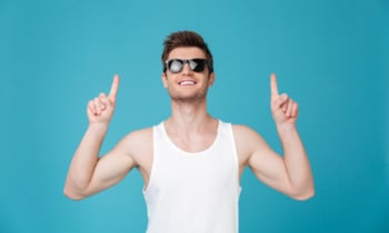 Cheerful young guy in sunglasses pointing