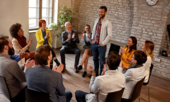 discussion business group- coworkers applauding man in group