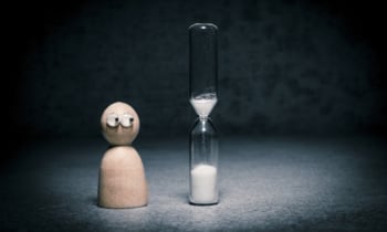 Time running out in hour-glass with nervous figure watching