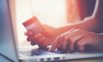 Hands holding credit card and using laptop. Online shopping