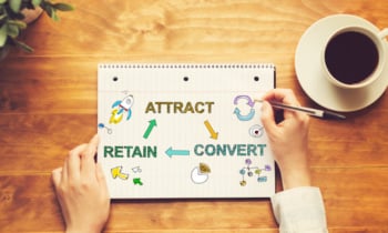 Attract Convert Retain text with a person holding a pen