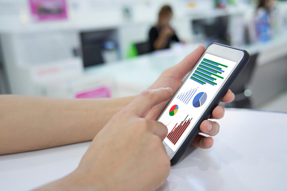 mao masculina segurando smartphone com estatisticas de KPI