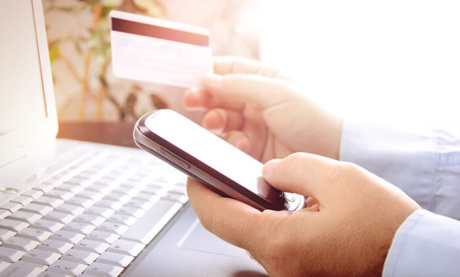 profissional acessando celular em frente a laptop