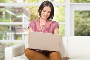 mulher sentada sorrindo ao olhar para tela de computador