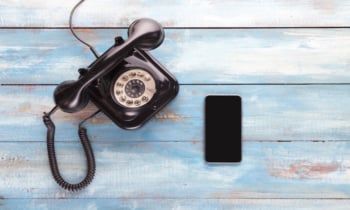 Old telephone and mobile phone on a blue wooden board