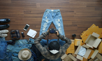 Top view of men shooting take a photo jeans pants and fashion accessories on wooden floor with postal parcel, Selling online ideas concept