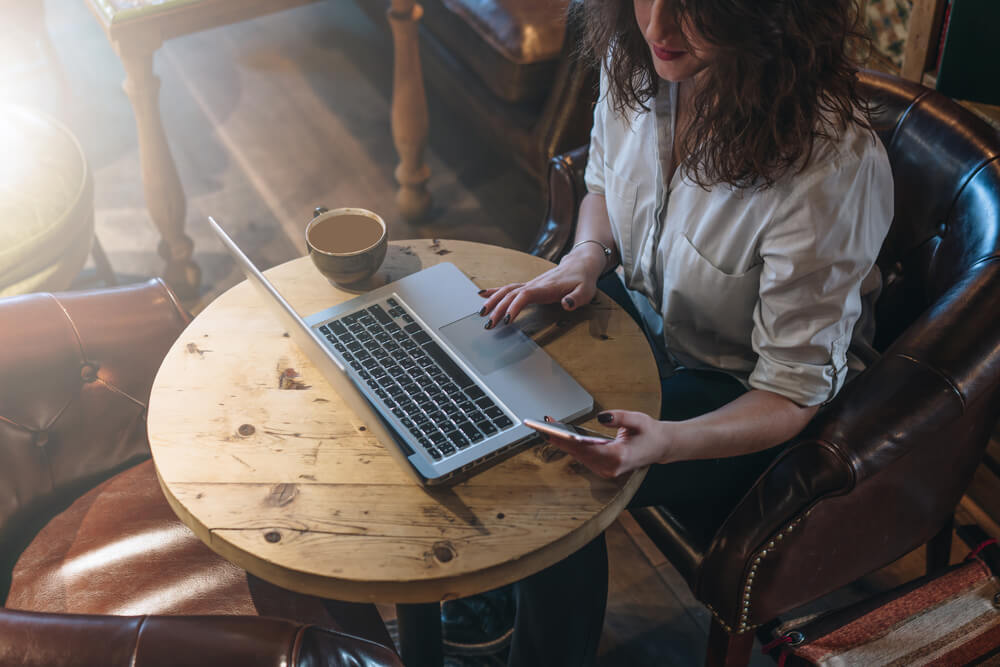 garota em café com laptop sobre mesa
ilustrando como usar a ferramenta mailchimp