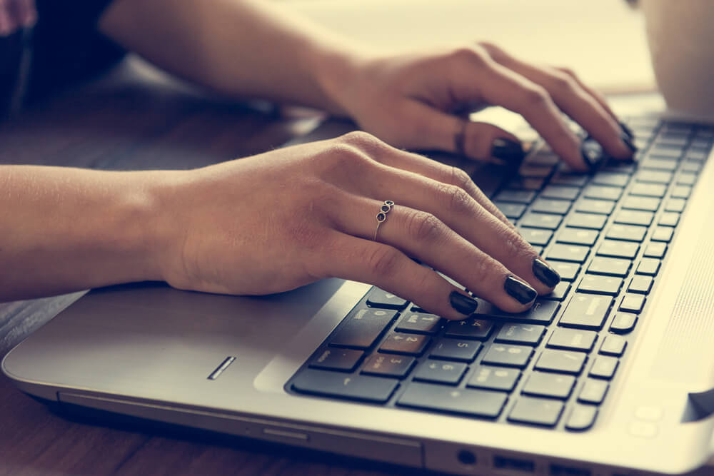 mão feminina digitando em laptop