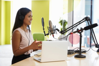 moça em gravação de áudio com fones de ouvido e a frente do laptop