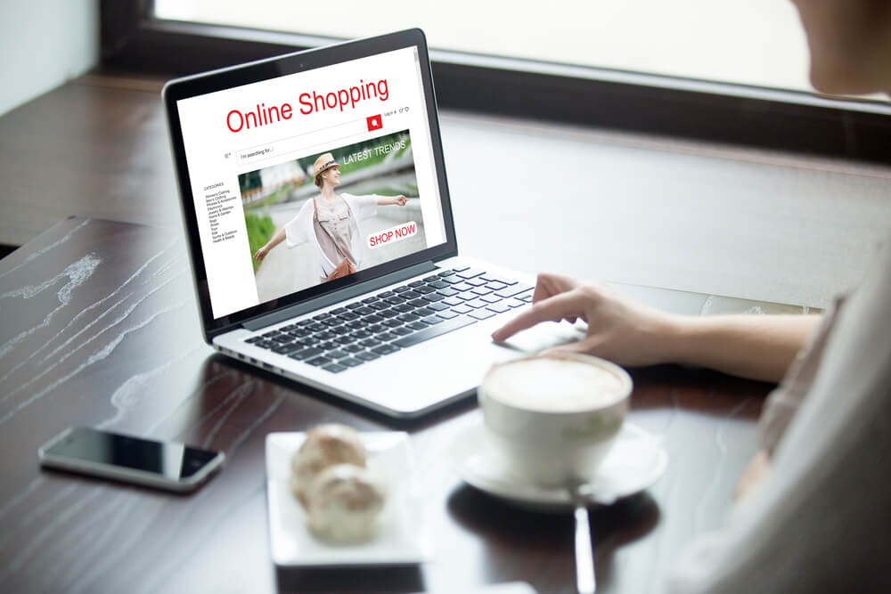 mulher acessando loja virtual em laptop em mesa junto de smartphone