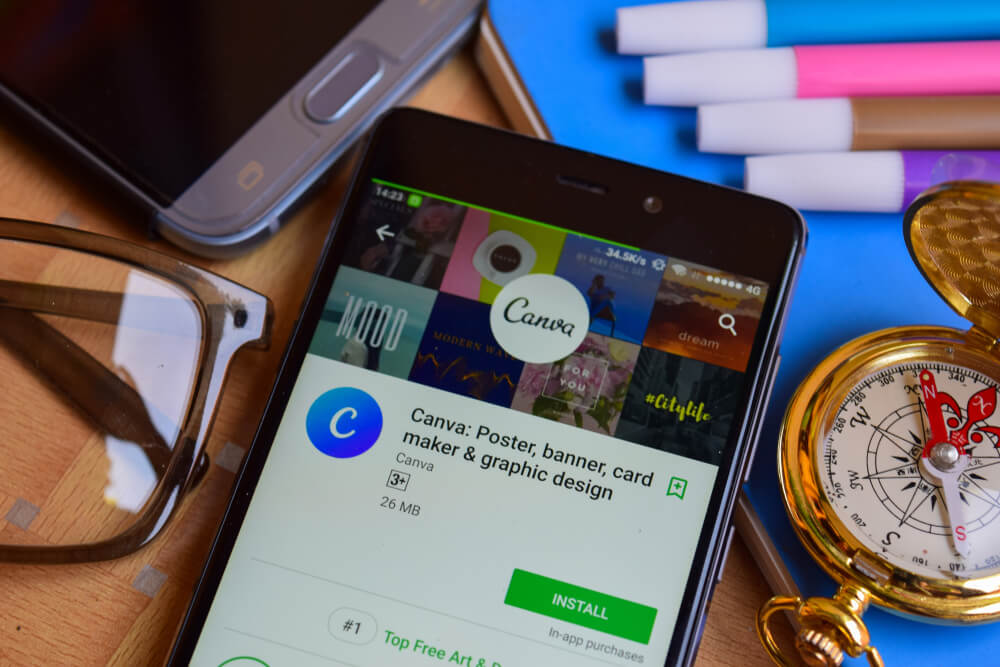 smartphones junto de canetas coloridas e tela de download do aplicativo mobile Canva