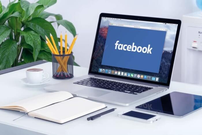 facebook sendo acessado em laptop sob mesa de escritorio
