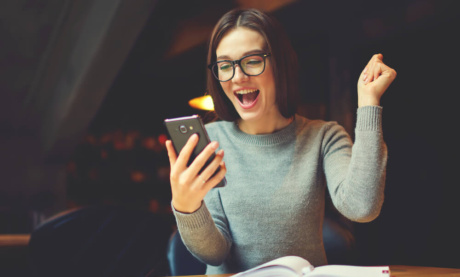 garota segurando smartphone e sinais de comemoração