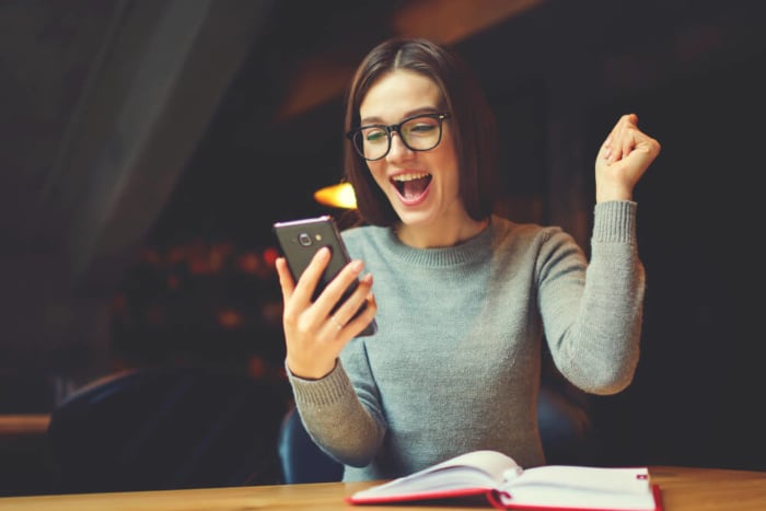 garota segurando smartphone e sinais de comemoração