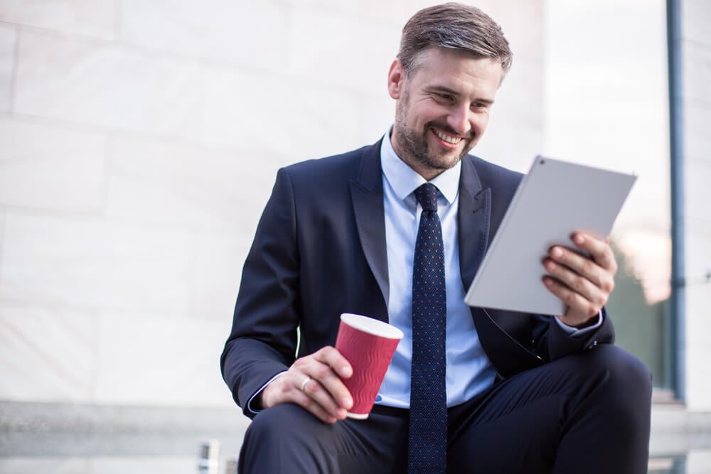 homem executivo sorridente olhando para tablet