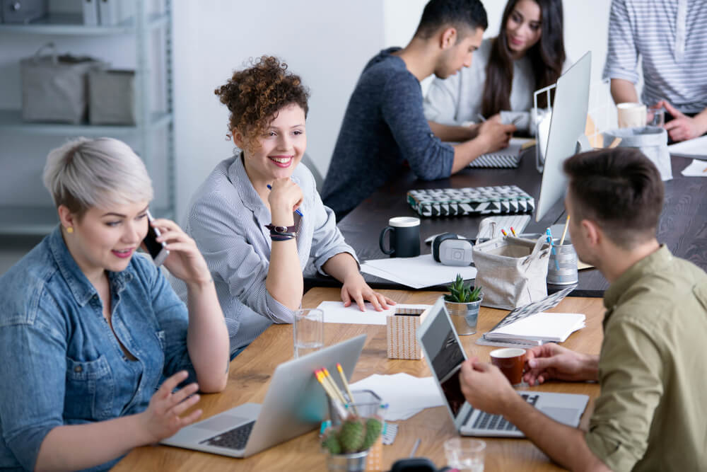 homens e mulheres trabalhando juntos em relaçoes publicas com laptops e materiais de escritorio