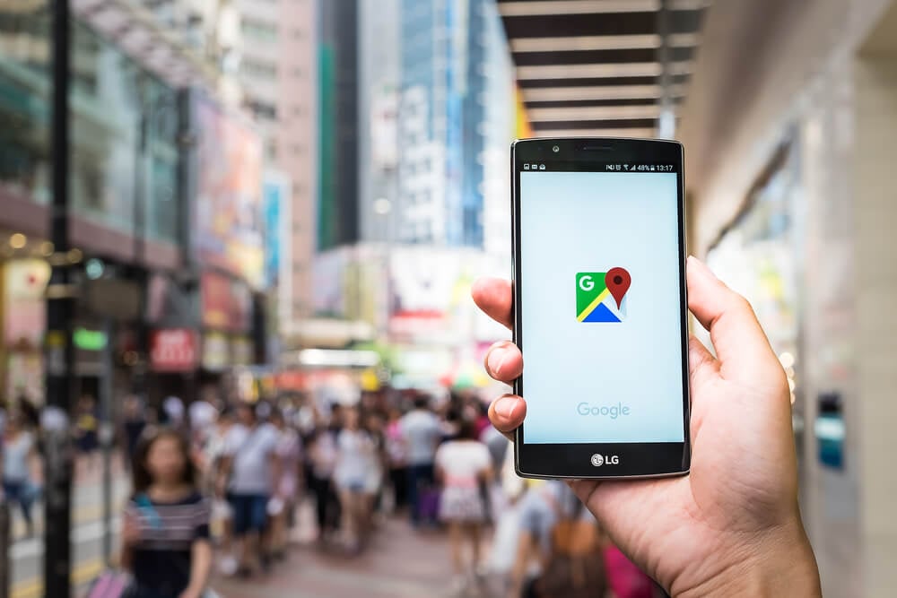 mao masculina em area urbana com smartphone em maos no aplicativo google maps