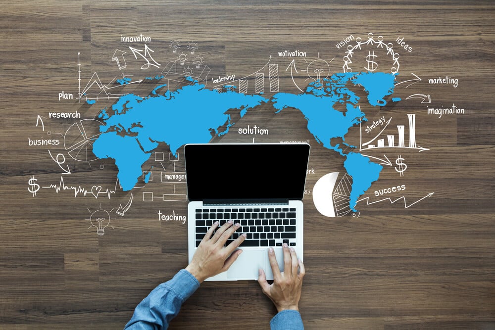 mãos masculinas acessando laptop e mapa mundi com anotações relacionados sobre estratégia e negócios