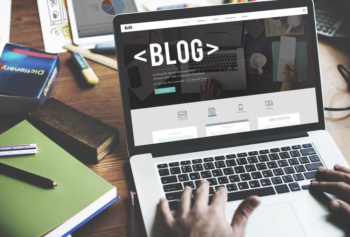 maos masculinas teclando em laptop em mesa de escritorio com a pálavra blog em tela