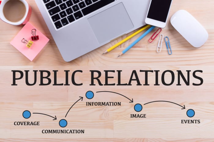 mesa com laptop e materiais de escritorio com a frase public relations e palavras relacionadas