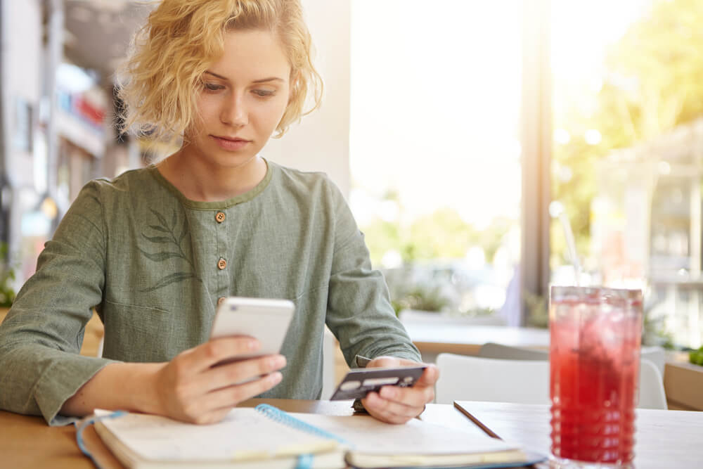 mulher cadastrando cartão de crédito em compras online no smartphone