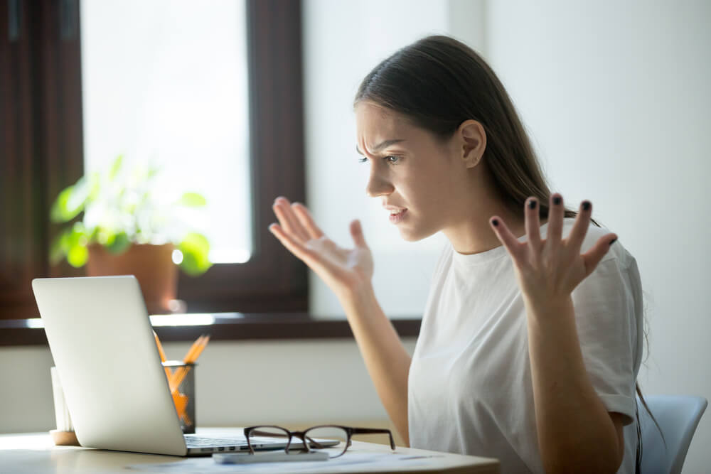 mulher com expressao raivosa em frente a laptop