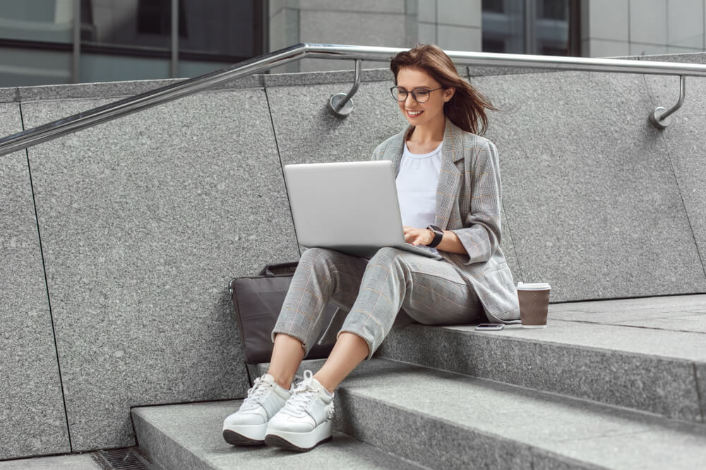 mulher profissional sentada em escada acessando laptop 