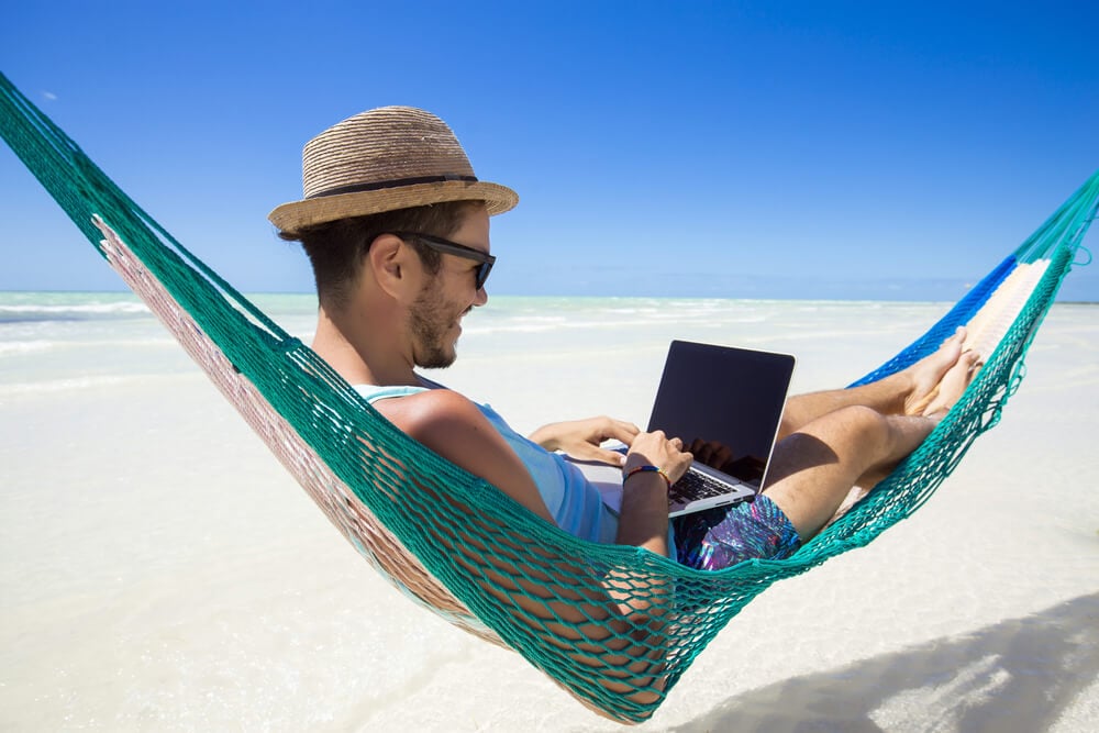nomade digital trabalhando em seu laptop em rede na praia