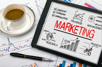 quadro branco com anotações do processo de administração de marketing em mesa de trabalho junto de xícara de café