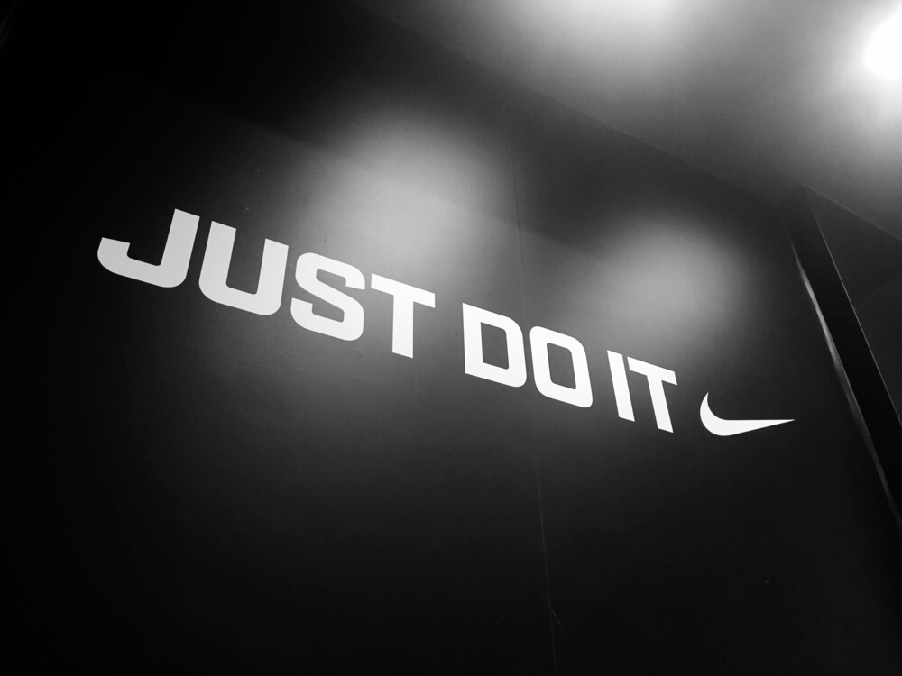 slogan junto de logo da marca de vestuário Nike