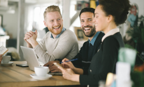 trio de colegas de trabalho sorridentes em mesa de café