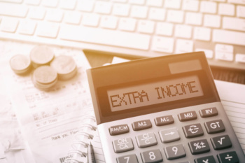 calculadora em mesa com computador com título renda extra