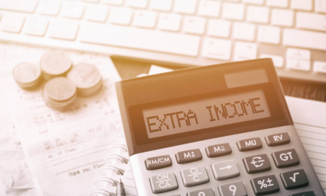 calculadora em mesa com computador com título renda extra